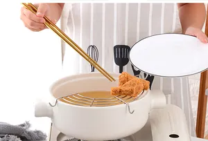 Close-up of extra long golden stainless steel chopsticks using a wire rack for fried food