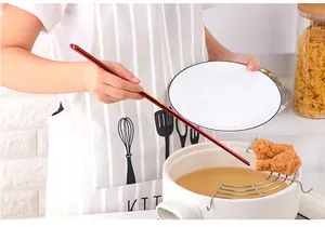 Extra long red 304 stainless steel chopsticks frying food from a pan in a kitchen