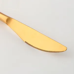 Gros plan sur le bord dentelé tranchant d'un couteau de table en acier inoxydable doré