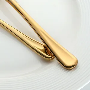 Détail des poignées de couverts en acier inoxydable doré poli sur une assiette en céramique