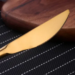Macro d'un couteau en acier inoxydable doré avec bord dentelé sur planche en bois