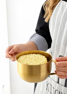 Detailed shot of a golden stainless steel noodle bowl with dual handles held by hands