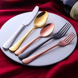 Polished stainless steel flatware set with hammered texture on a white dinner plate