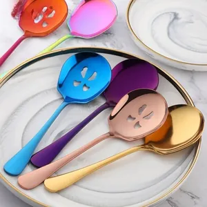 Macro detail of multi-color stainless steel serving spoons on a white ceramic plate