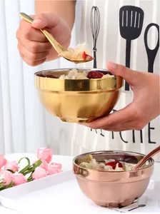 Close-up of double-walled insulated stainless steel bowls and spoons in gold finish