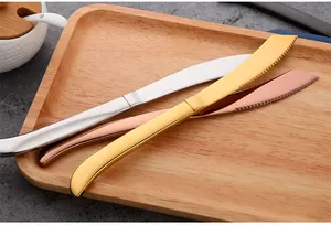 Detailopname van gekartelde roestvrijstalen steakmessen in zilver, goud en roségoud-afwerking