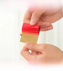 Close-up of golden brushed stainless steel adhesive hook with red peel-off backing