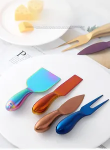 Set of four colorful stainless steel cheese knives and forks displayed on a white plate