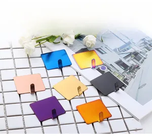 Detail of seven colored brushed metal hooks in blue gold and black on white tile wall