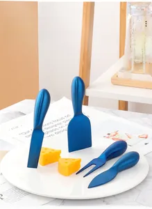 Detailed view of 4-piece matte blue stainless steel cheese knife set on marble surface