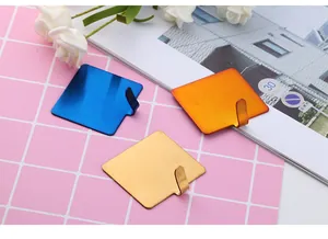 Close-up of square metal adhesive wall hooks in blue, gold, and copper red finishes