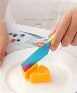 Action shot of rainbow titanium cheese knife cutting soft cheese on white ceramic plate
