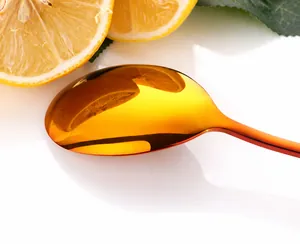 Gros plan d'une cuillère en acier inoxydable 304 dorée polie avec finition miroir et citron
