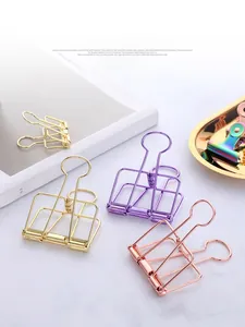 Close-up of colorful metal binder clips in gold and rose gold on a marble desk