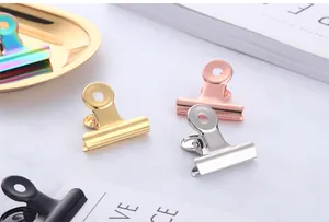 Detailed view of colorful metal binder clips in gold and silver on marble background