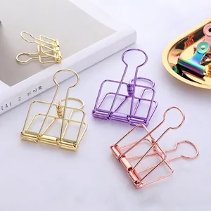 Colorful hollow wire binder clips in gold, purple and rainbow finish on marble surface