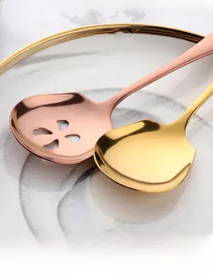 Polished gold solid spoon and rose gold hollow petal strainer on marble plate
