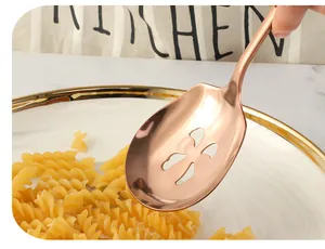 Close-up of rose gold stainless steel slotted spoon picking up pasta on marble table