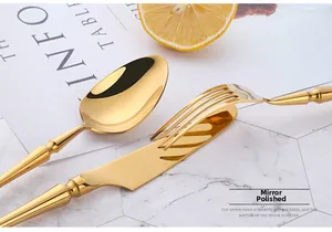 Mirror polished gold cutlery set with textured handles on marble surface background