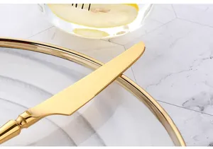 Close-up of golden stainless steel steak knife with sharp serrated blade on marble