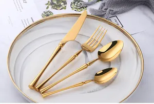Close-up of polished gold 4-piece stainless steel cutlery set on elegant dinnerware