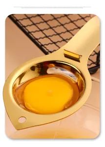 Vue macro d'un séparateur d'oeuf en acier inoxydable doré filtrant le jaune d'oeuf