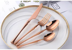 Close-up of rose gold stainless steel cutlery set on marble plate for fine dining