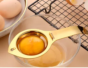 Détail d'un séparateur d'oeuf en acier inoxydable doré posé sur un bol en verre