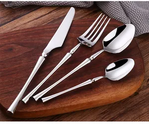 Polished gold stainless steel flatware set on dark wood tray with elegant tapered handles