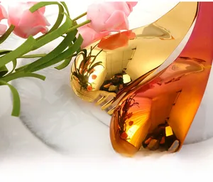 Close-up of polished curved stainless steel spoons in gold and rainbow mirror finish
