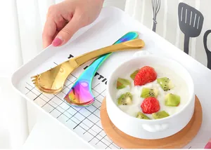 Creative gold and iridescent stainless steel spork spoons next to strawberry yogurt dessert