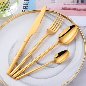 Détail d'un ensemble de 4 couverts en acier inoxydable doré sur une assiette blanche