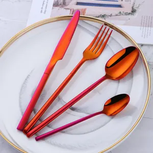 Rainbow iridescent stainless steel cutlery set with V-shaped handle on a white marble plate