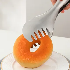 Détail d'une pince en inox saisissant un donut avec sa pointe dentelée ajourée