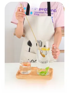 Extended gold bar spoon with spiral handle stirring lemon drink in a tall glass pitcher