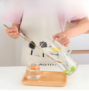 Close-up of golden spiral mixing spoon in glass pitcher with lemon and mint leaves