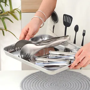 Gros plan de pinces de service et plateau en acier inoxydable brossé pour buffet