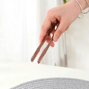 Détail de pinces de cuisine en acier inoxydable bronze avec bord dentelé ergonomique
