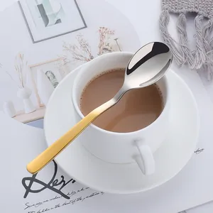 Close-up of a dual-color V-shaped spoon resting on a coffee cup with mirror finish