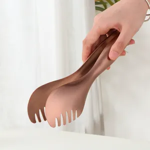 Gros plan d'une pince de cuisine en acier inoxydable or rose avec bords dentelés