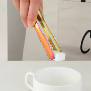 Pince à sucre arc-en-ciel en inox avec bords dentelés saisissant un sucre blanc