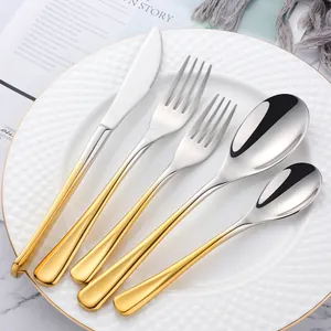 Dettaglio del set di posate da 5 pezzi in acciaio inox argento e oro su un piatto