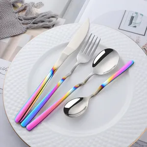 Detail of rainbow gradient handle stainless steel cutlery set on a white ceramic plate