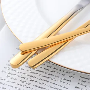 Polished gold stainless steel cutlery set with modern V-shape design on white plate