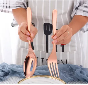 Close-up of rose gold stainless steel serving fork and slotted spoon with mirror finish