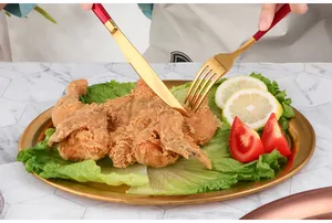 Nahaufnahme von goldenem Edelstahltablett mit rot-goldenem Besteck auf Marmortisch