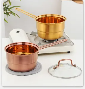 Close-up of stainless steel milk pot set with glass lid and long hollow handles on stove