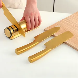 Close-up of golden cylindrical knife sharpener and stainless steel knife set on wood board