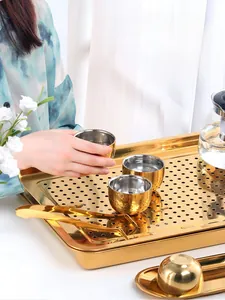 Detail of golden stainless steel tea tray set featuring a rectangular drainage plate