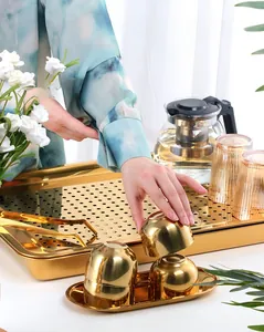 Close-up of golden stainless steel tea tray set with mirror finish and drainage plate